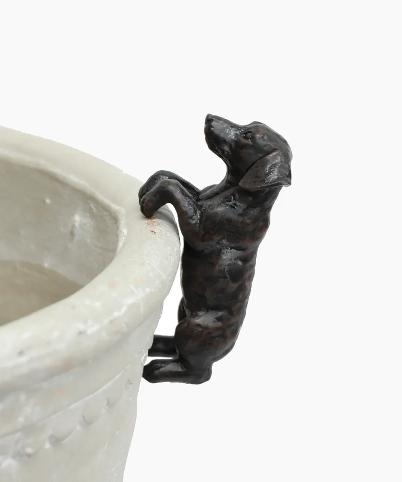 Decorative metal dog figurine on a white ceramic planter