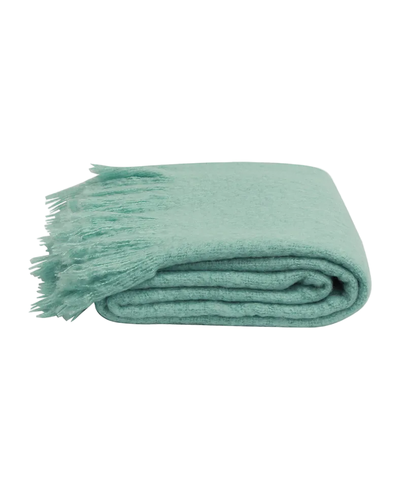 Folded teal blanket with tassels on a white background