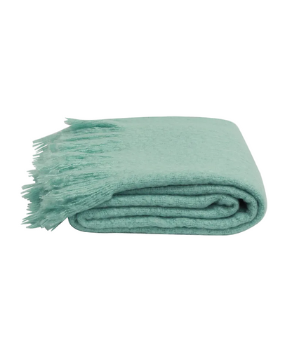 Folded teal blanket with tassels on a white background