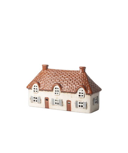 Small ceramic house with a thatched roof on a white background