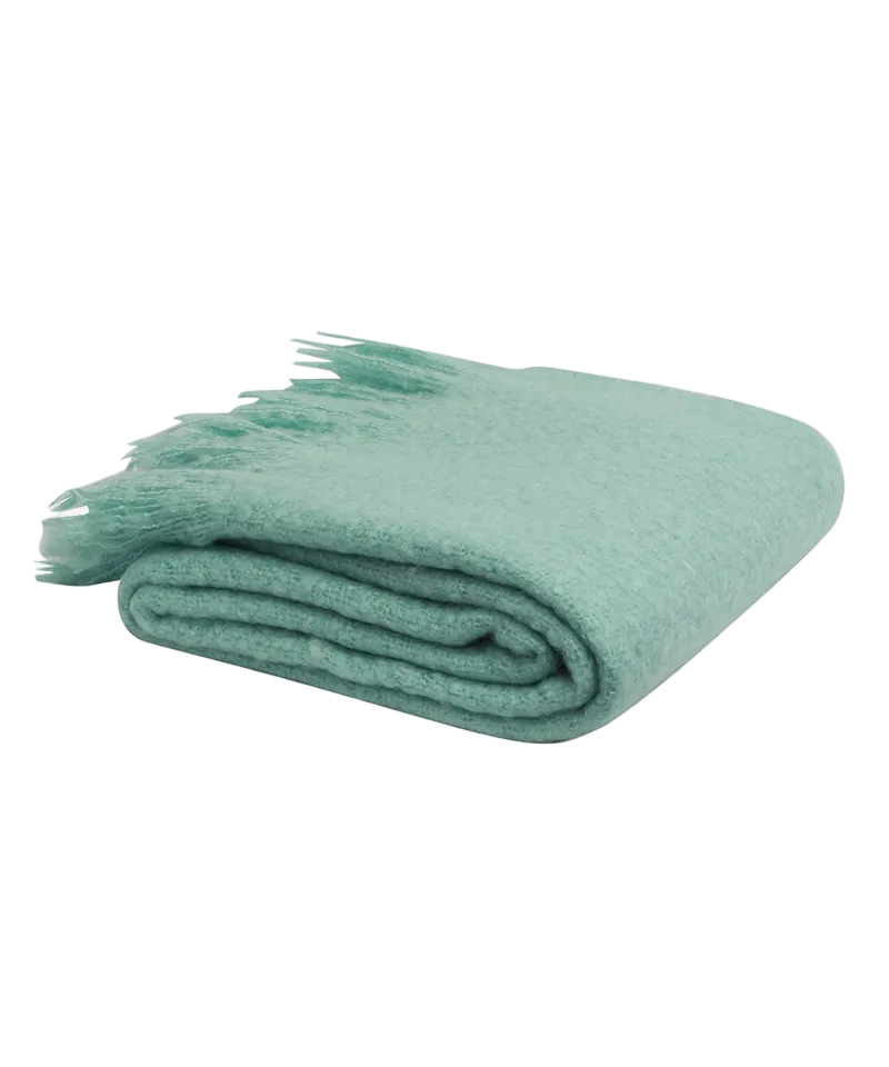 Folded teal blanket with tassels on a white background